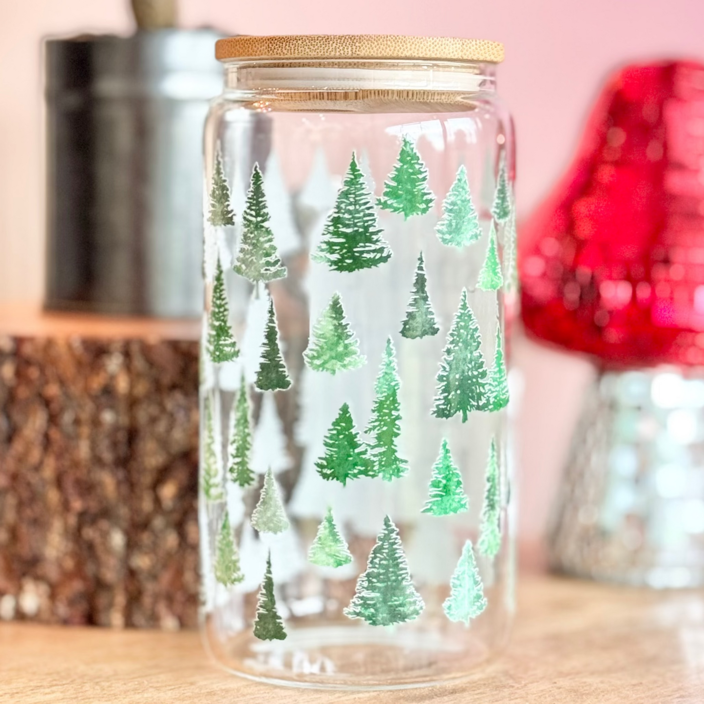 Glass jar with tree pattern on a wooden surface with decorative items in the background