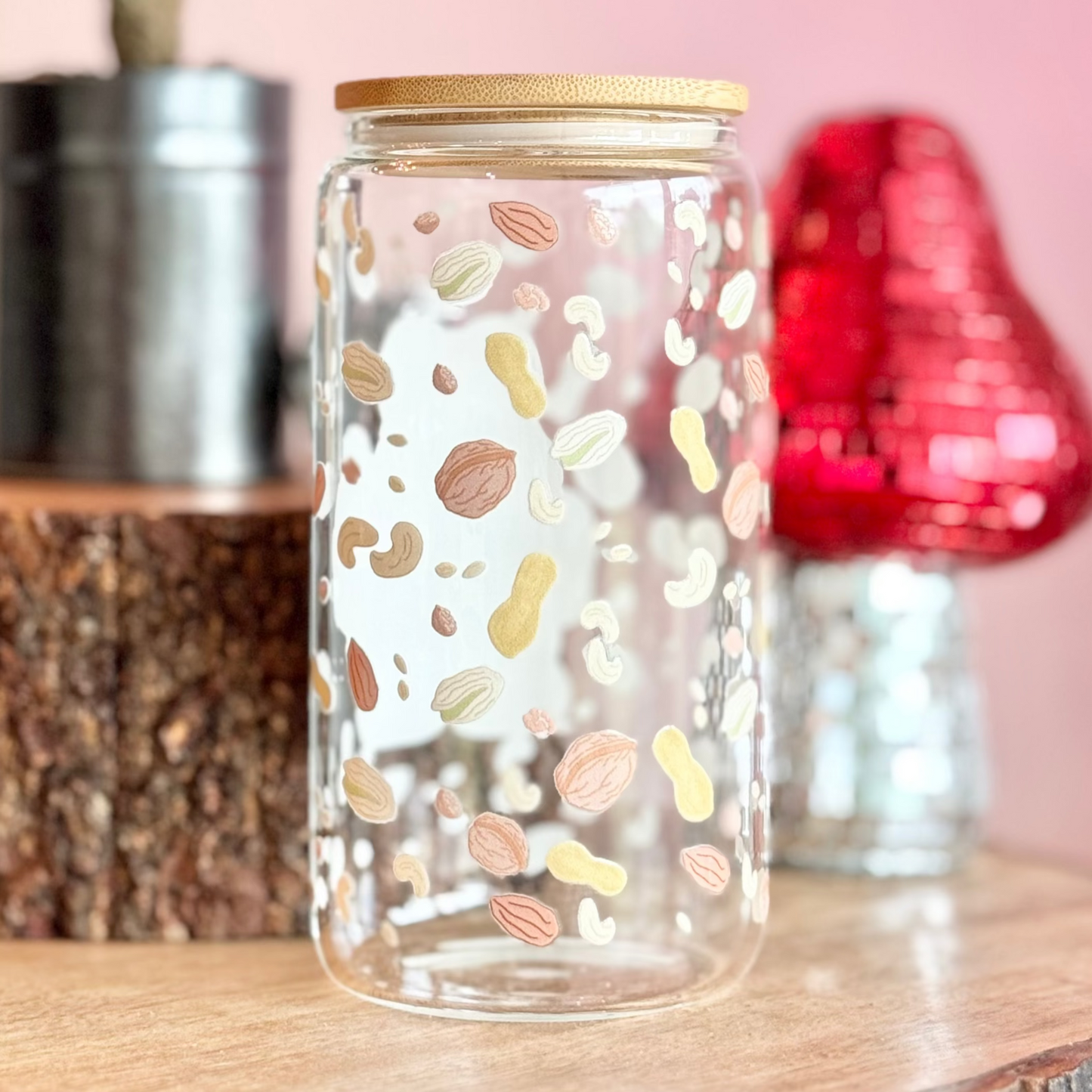 Decorative glass jar with colorful patterns on a wooden surface with a pink background.