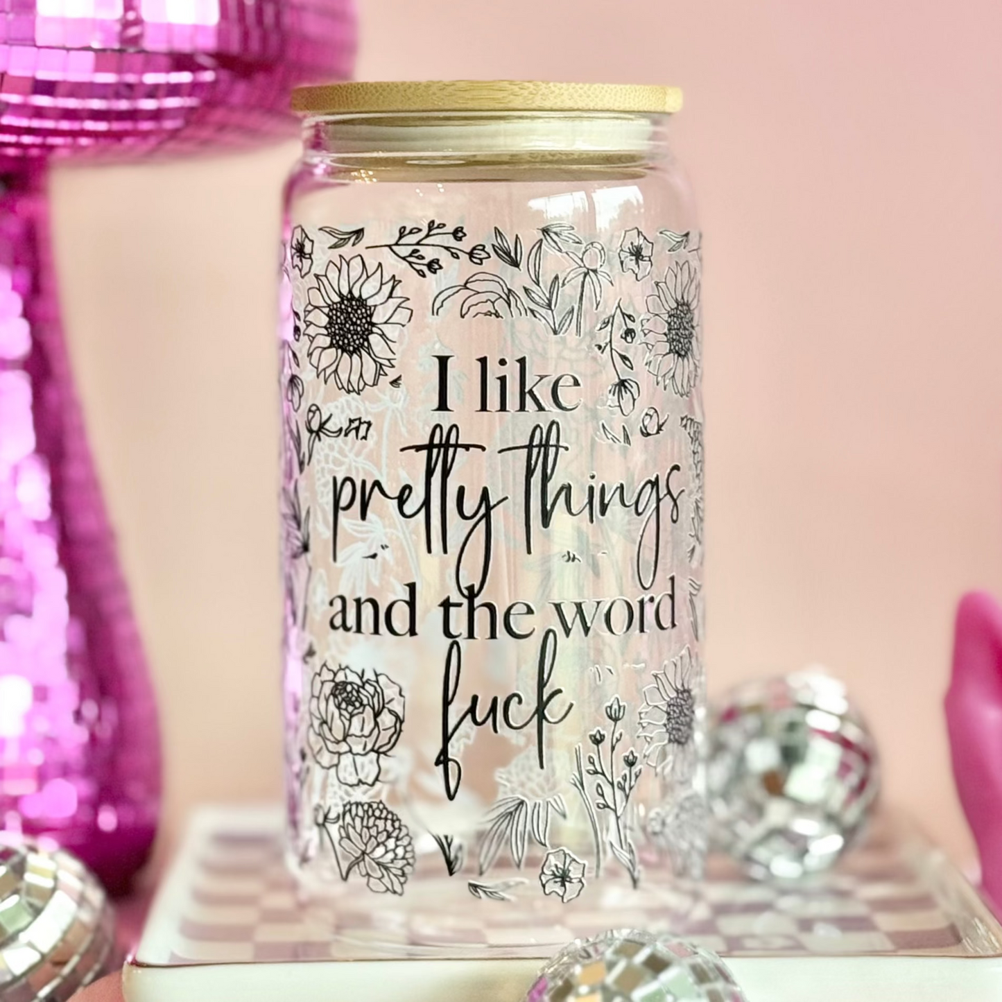 Glass jar with floral designs and text on a pink background