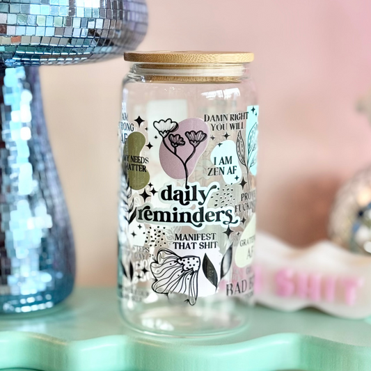 Glass jar with decorative text and illustrations on a light blue stand with a pink background