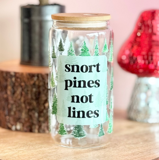 Glass jar with 'snort pines not lines' text on a wooden surface with decorative items.