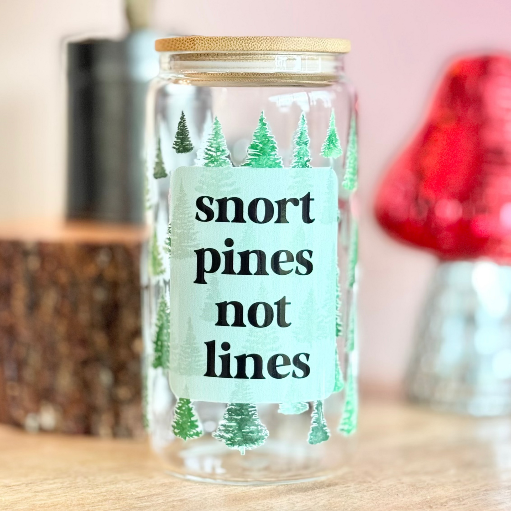 Glass jar with a humorous label on a wooden surface with decorative items in the background
