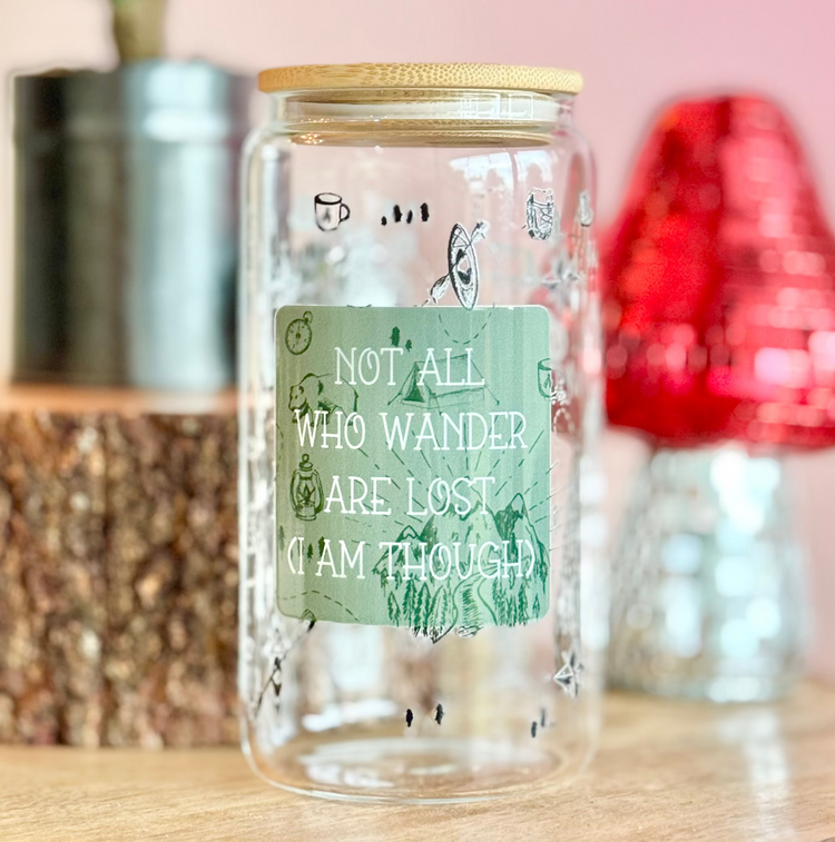 Clear glass jar with a green label on a wooden surface with decorative items in the background.
