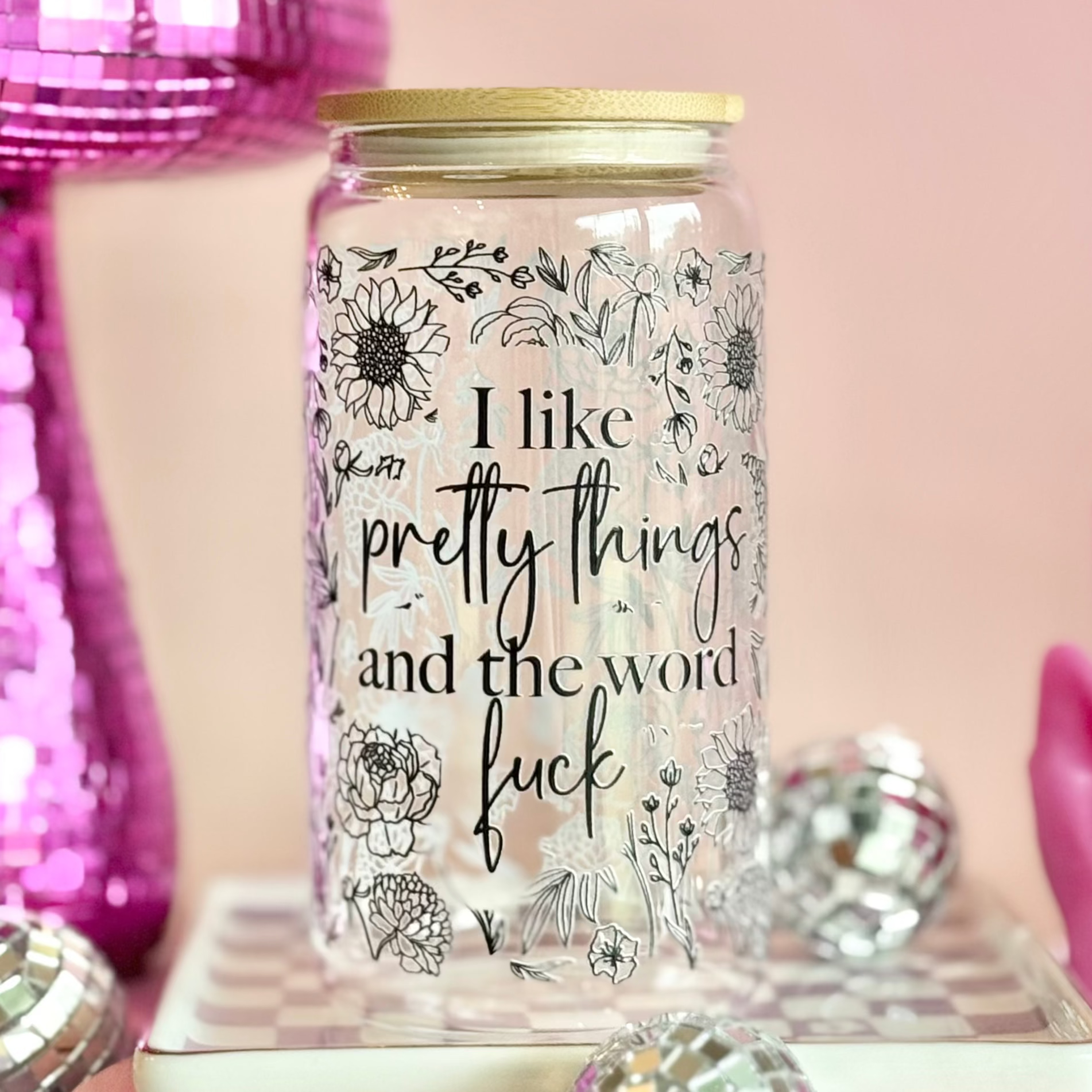 Glass jar with floral designs and text on a pink background