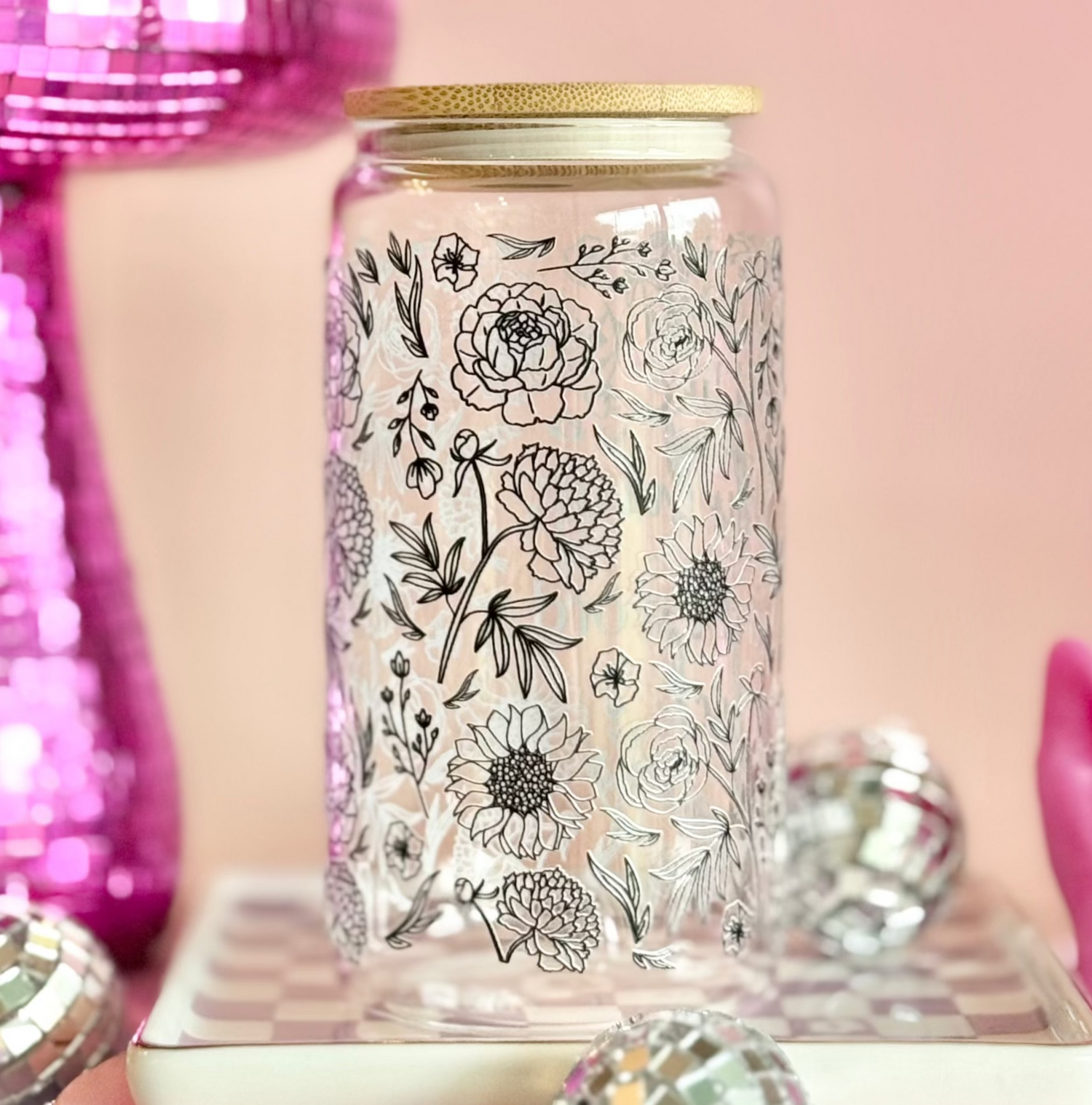 Decorative jar with floral design on a pink background with disco ball and string lights.