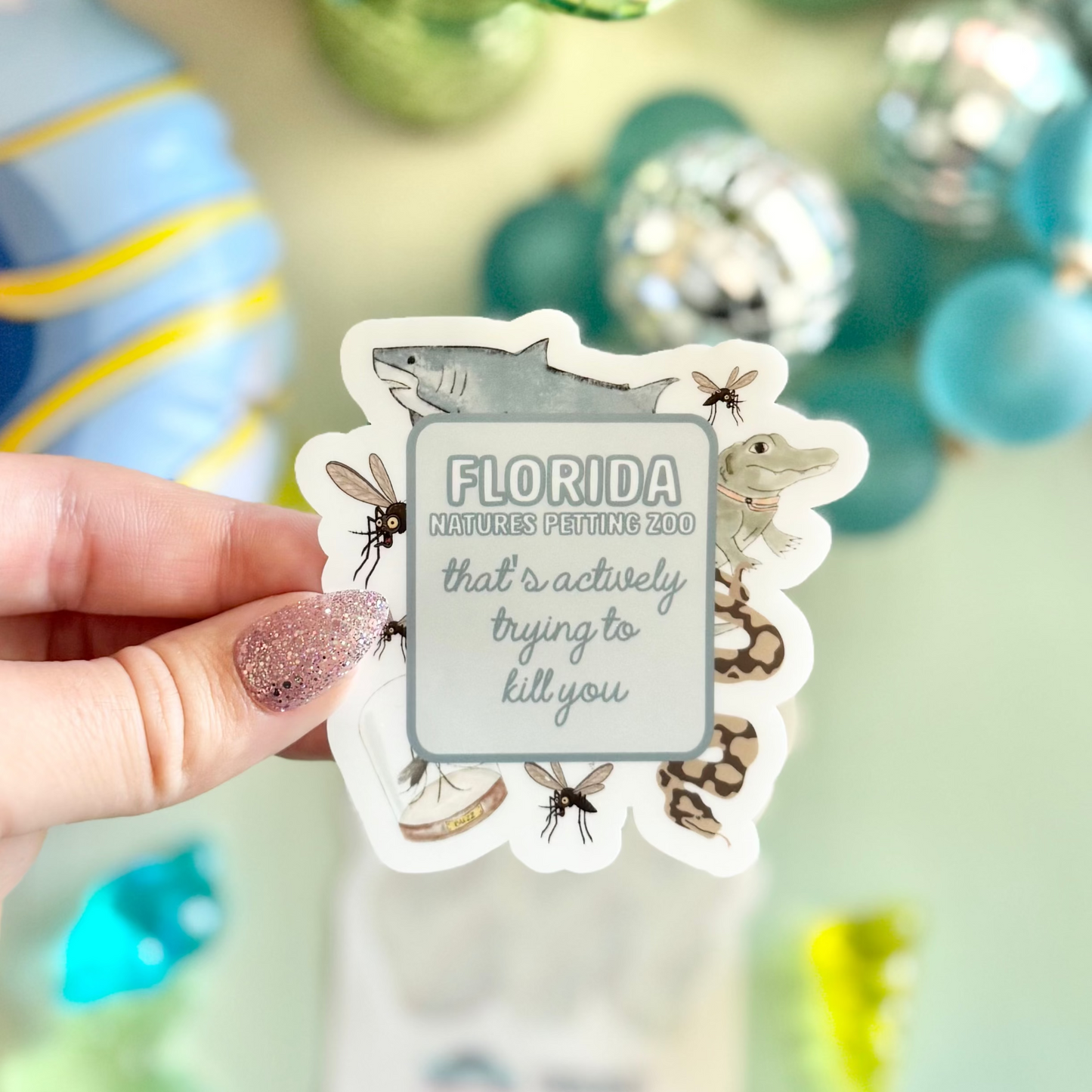 Hand holding a 'Florida' sticker with decorative items in the background