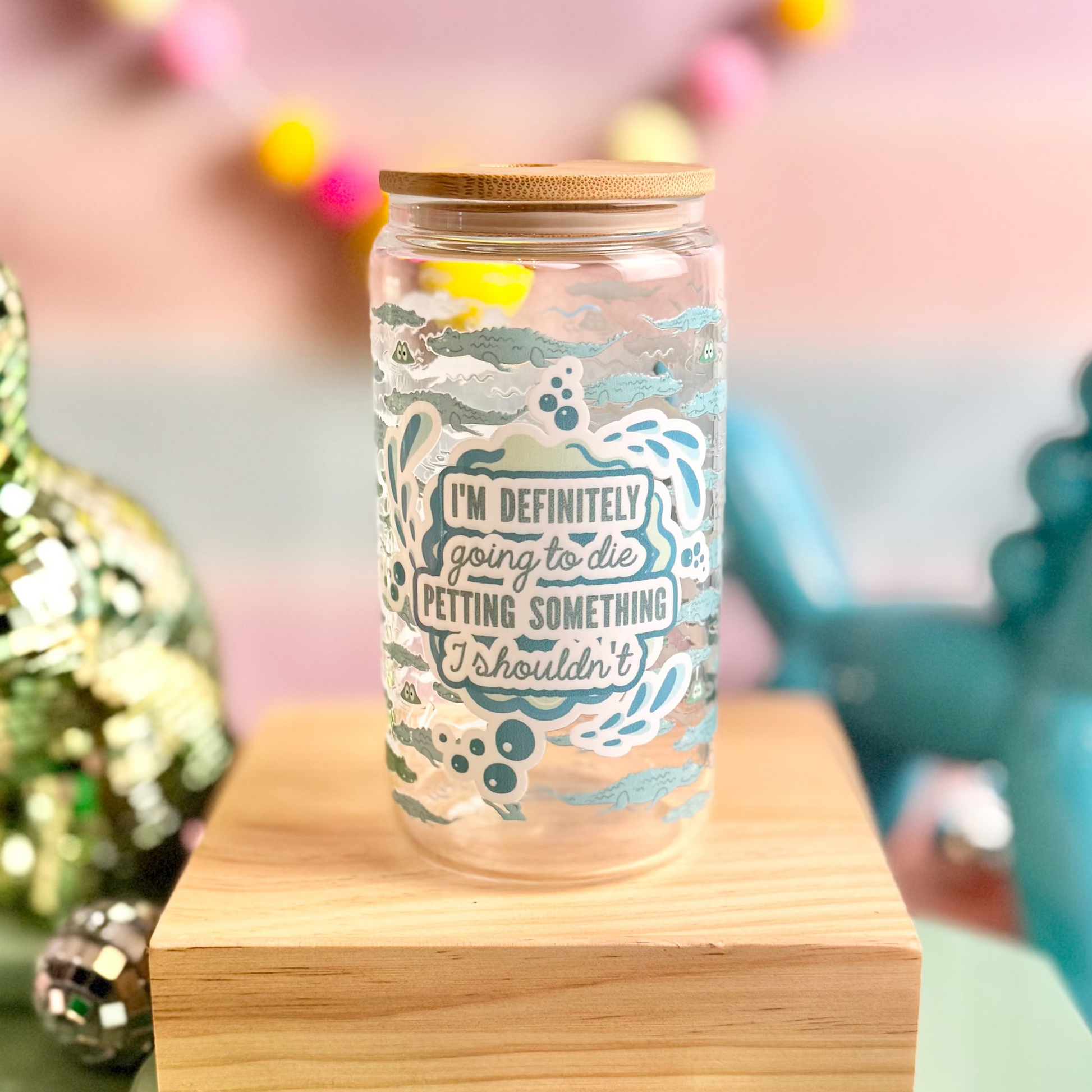Clear glass jar with text on a wooden stand, surrounded by colorful decorations including a gold dinosaur and blue unicorn figurine.