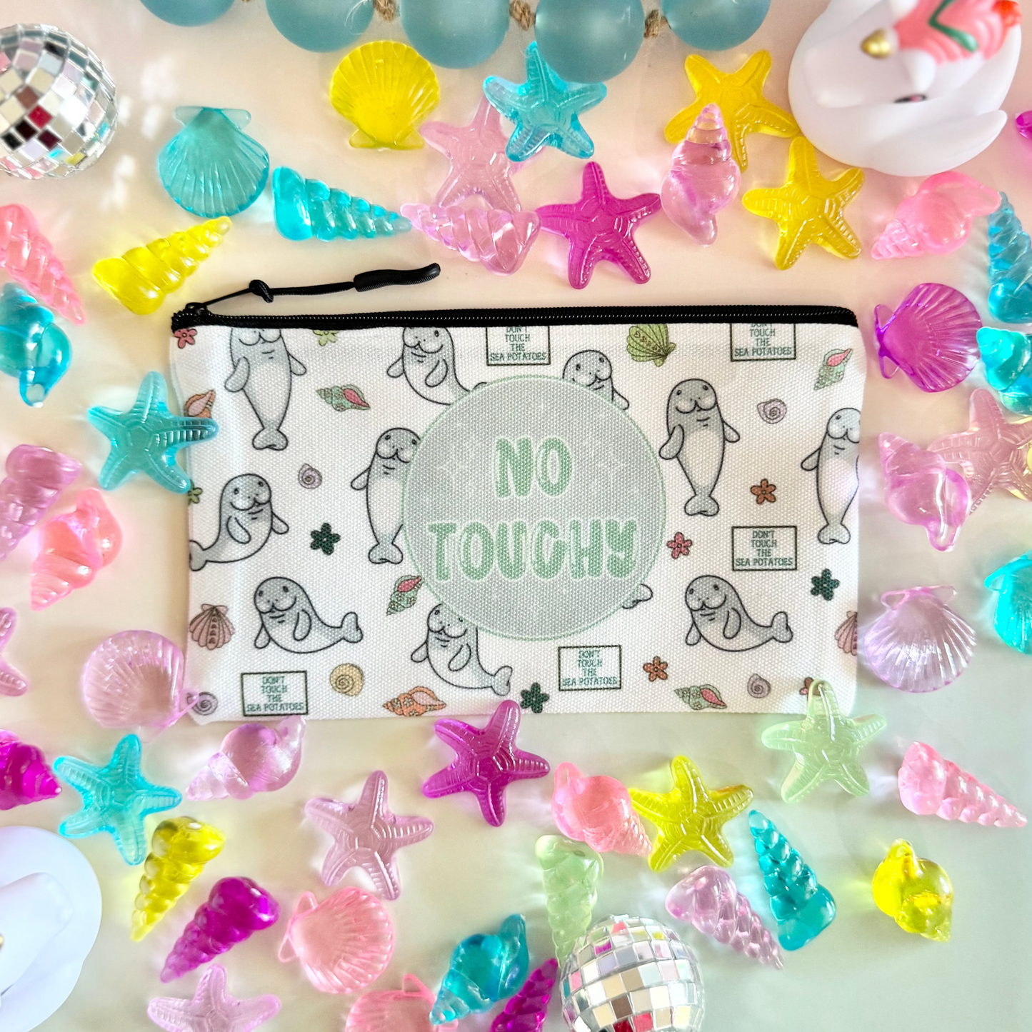 Colorful sea-themed accessories including a pouch with 'No Tough' text, surrounded by starfish, shells, and disco balls on a gradient background.