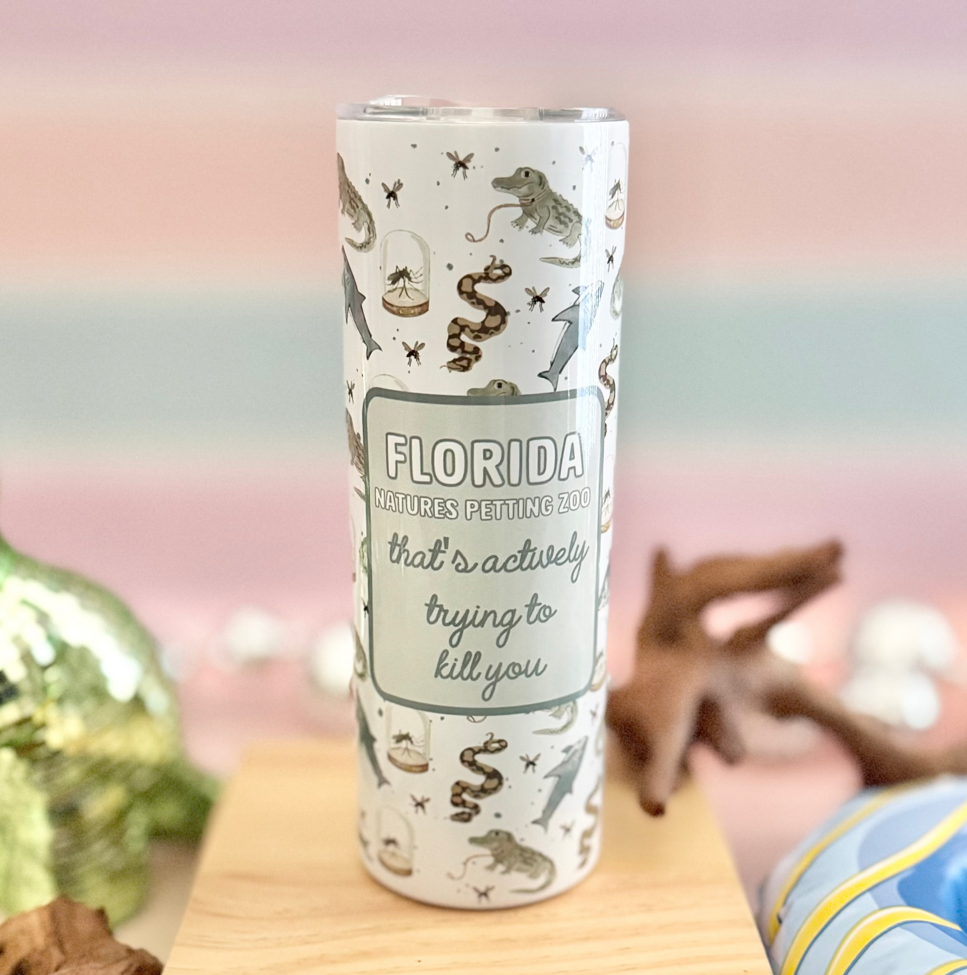 Tumbler with decorative design on a wooden block with decorative items in the background